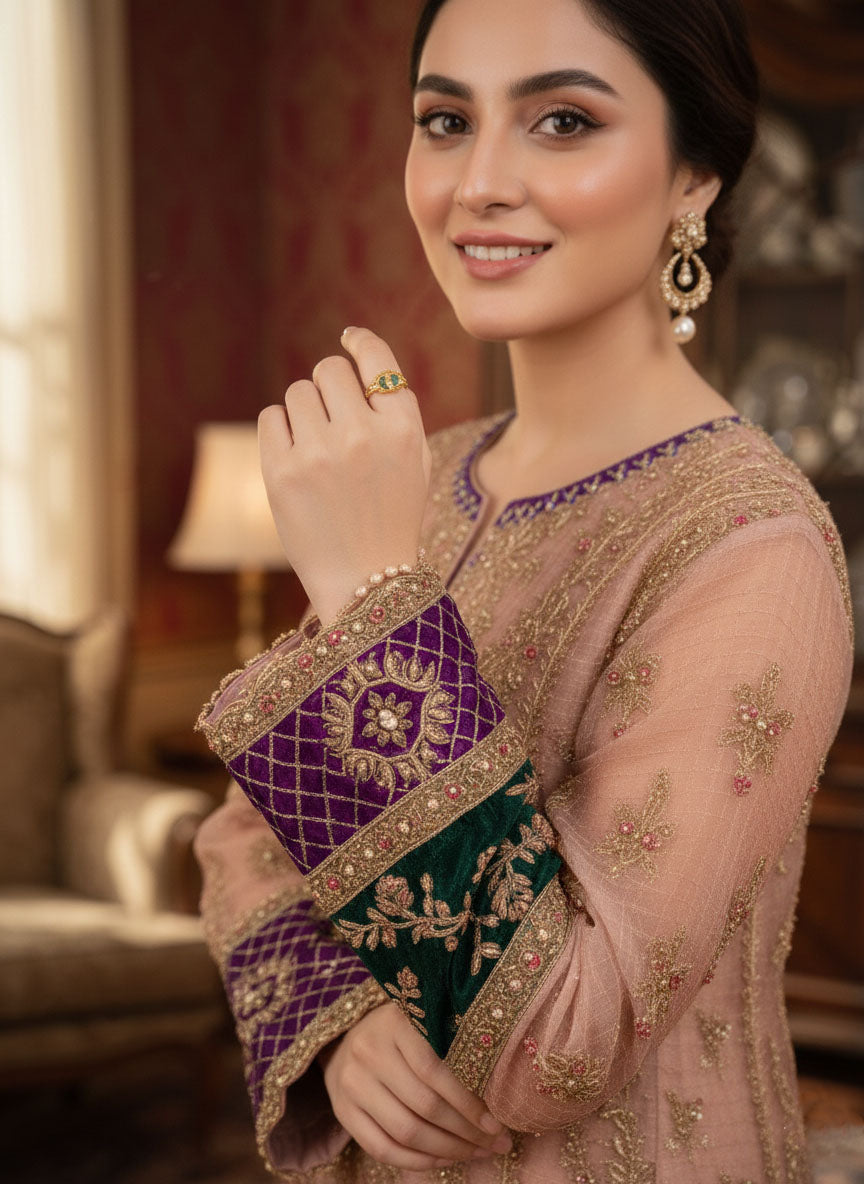 Woman wearing embroidered Pakistani formal wear suit with gold and purple festive detailing.