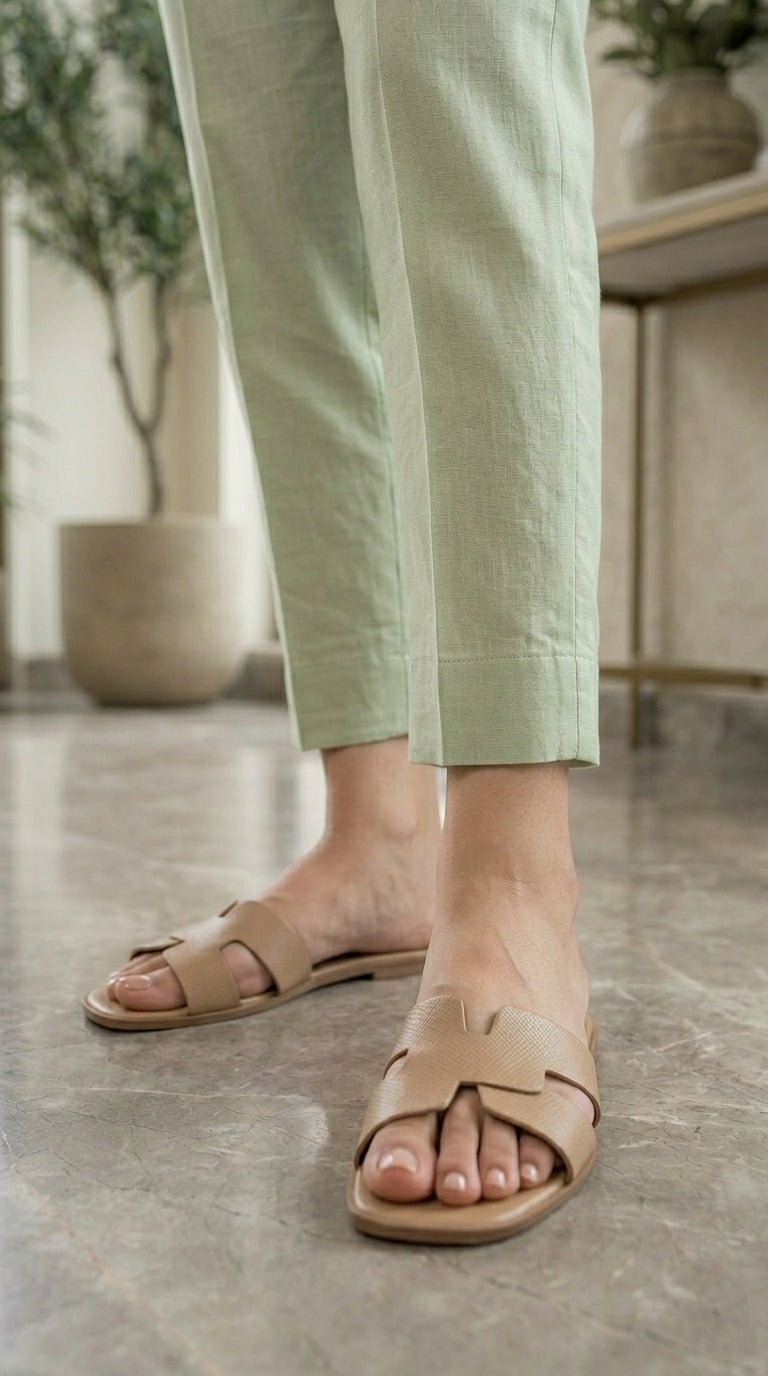 Person wearing beige sandals and light green pants on a marble floor.