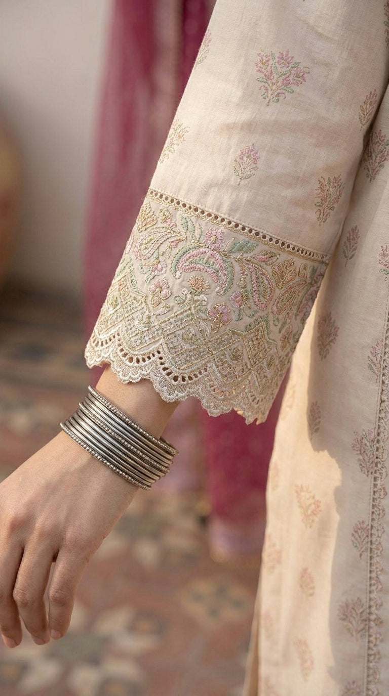 Close-up of a person wearing a light pink embroidered traditional outfit with intricate patterns.