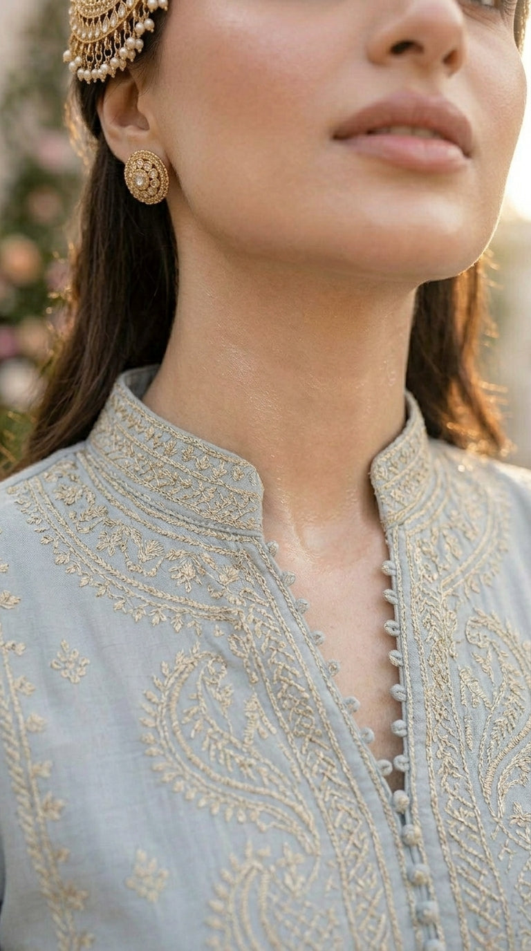 Close-up of a person wearing a light blue embroidered traditional outfit with gold detailing.