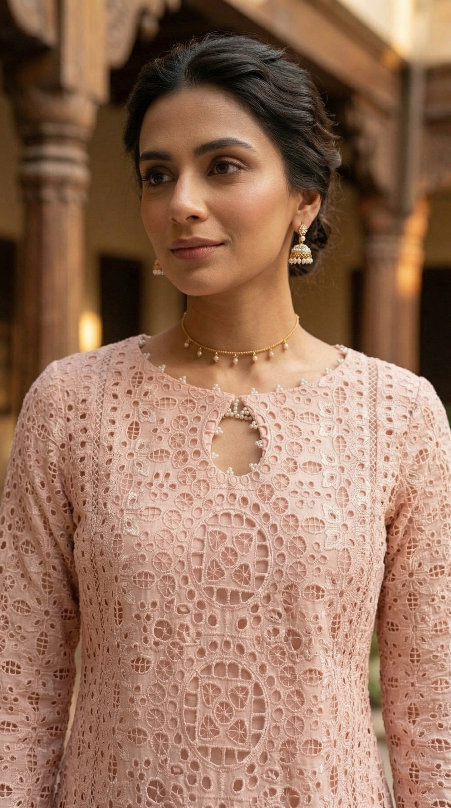 Woman wearing a patterned dress with intricate designs in an indoor setting.