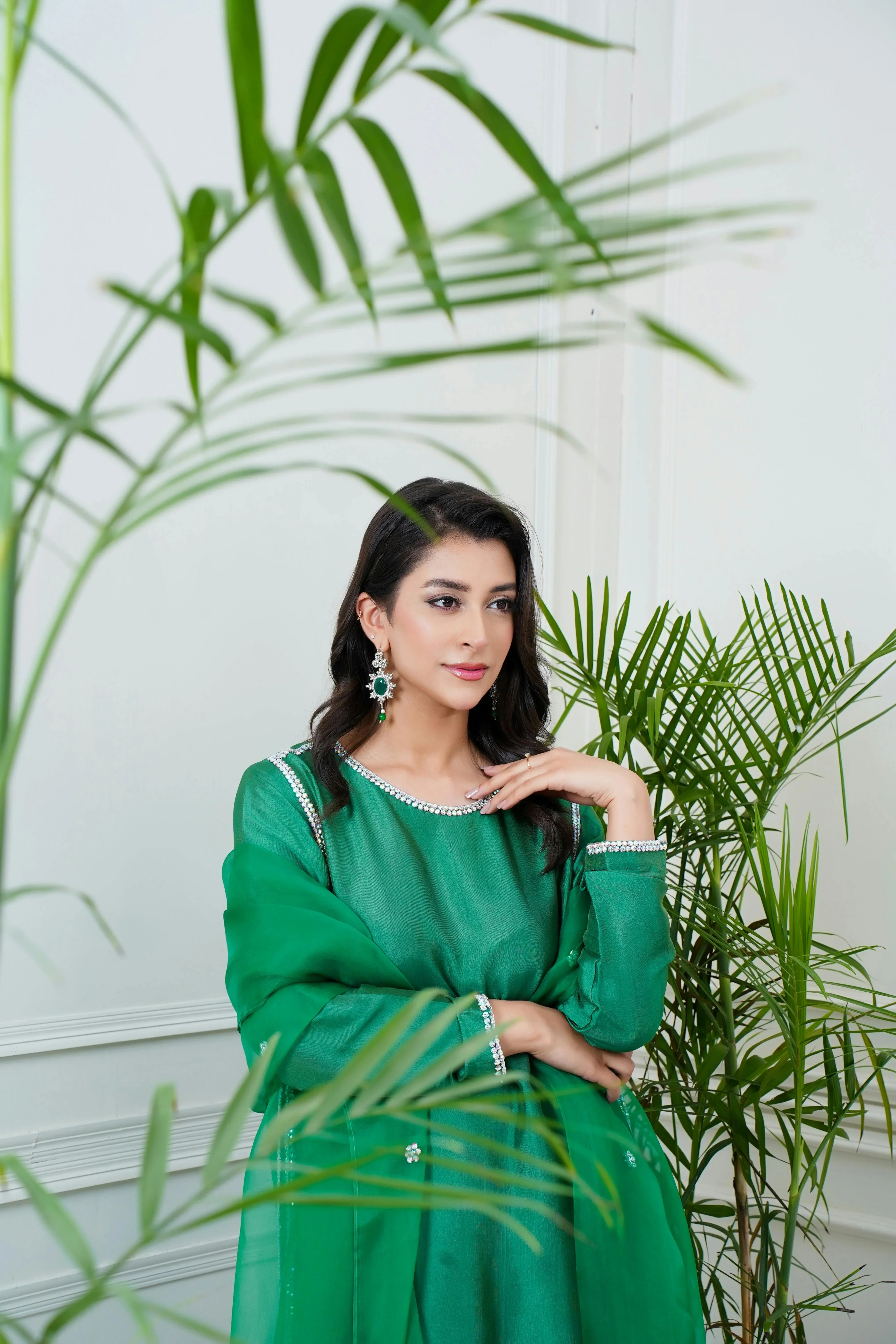 Woman in green Pakistani dress, festive wear, designer suit Pakistan, indoor setting with plants